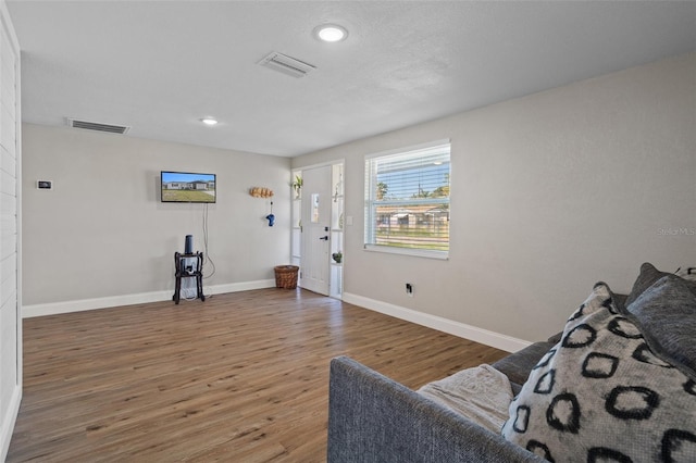 living area with recessed lighting, visible vents, baseboards, and wood finished floors