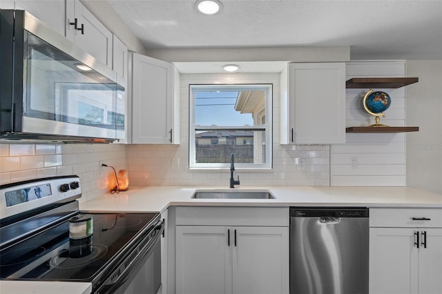 kitchen with tasteful backsplash, a sink, stainless steel appliances, white cabinetry, and open shelves