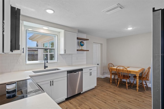 kitchen featuring visible vents, a sink, open shelves, stainless steel dishwasher, and white cabinetry