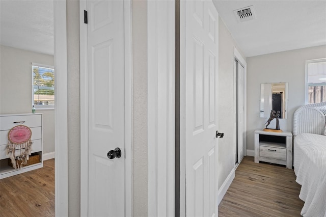 corridor with visible vents, baseboards, and wood finished floors