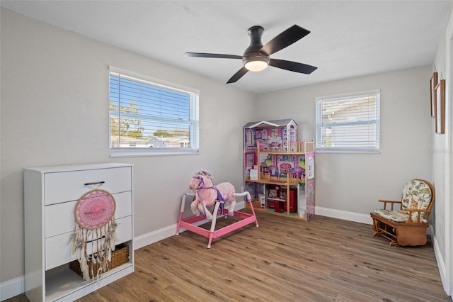 recreation room featuring a ceiling fan, plenty of natural light, wood finished floors, and baseboards