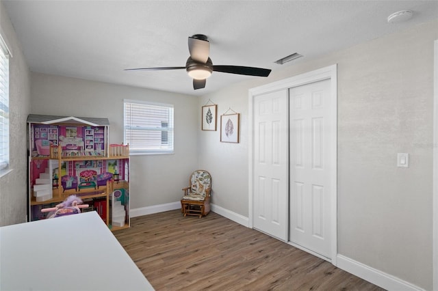 recreation room featuring visible vents, a ceiling fan, baseboards, and wood finished floors