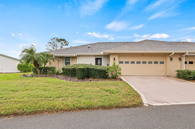 ranch-style home featuring stucco siding, driveway, an attached garage, and a front lawn