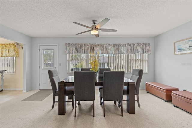 dining room featuring a textured ceiling, ceiling fan, baseboards, and light carpet