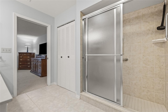 full bath featuring a closet, tile patterned floors, a stall shower, and baseboards