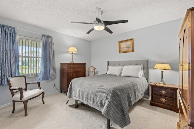 bedroom featuring a ceiling fan, light colored carpet, baseboards, and a textured ceiling