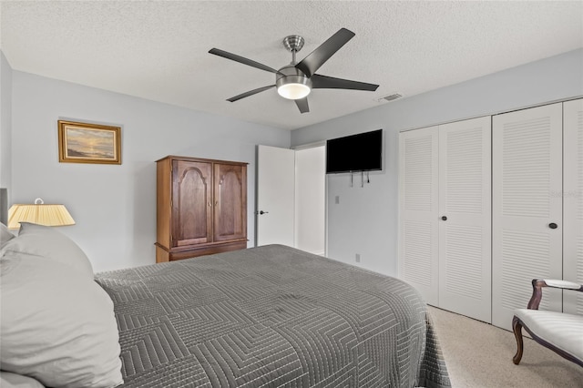 bedroom with visible vents, light carpet, a closet, a textured ceiling, and a ceiling fan