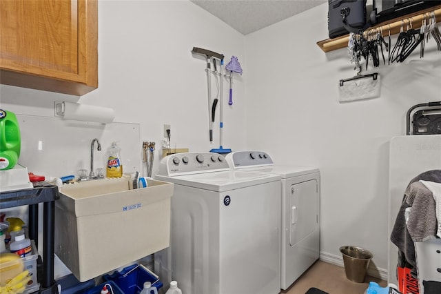 laundry area featuring a sink, baseboards, cabinet space, and independent washer and dryer