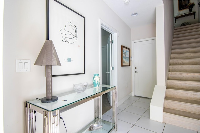 hallway featuring stairway and light tile patterned flooring