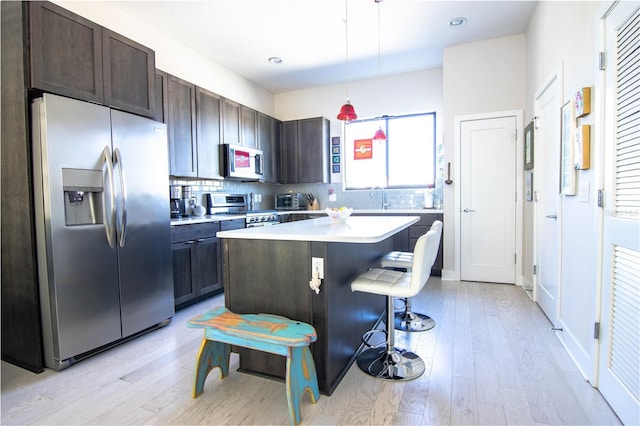 kitchen with light countertops, decorative backsplash, appliances with stainless steel finishes, a sink, and dark brown cabinets