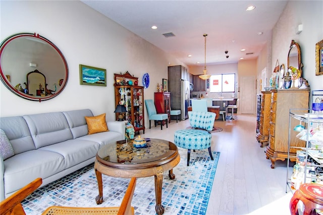 living room with light wood-type flooring, visible vents, and recessed lighting