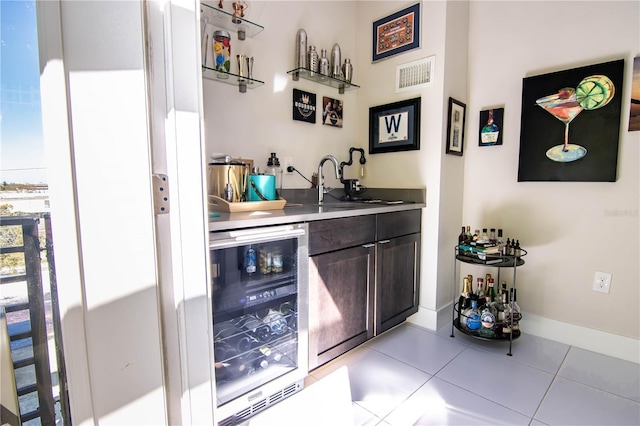 bar featuring light tile patterned flooring, beverage cooler, a sink, visible vents, and wet bar