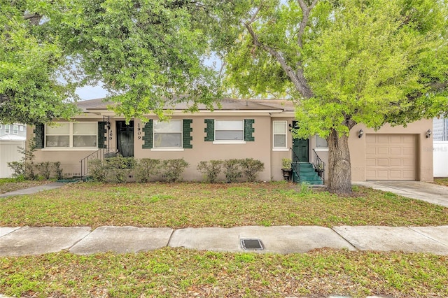 single story home featuring a front lawn, a garage, driveway, and stucco siding