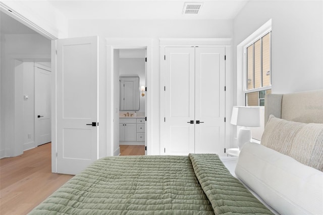 bedroom featuring light wood-type flooring, a closet, visible vents, and ensuite bathroom