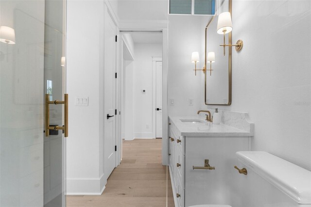 bathroom featuring baseboards, visible vents, toilet, wood finished floors, and vanity