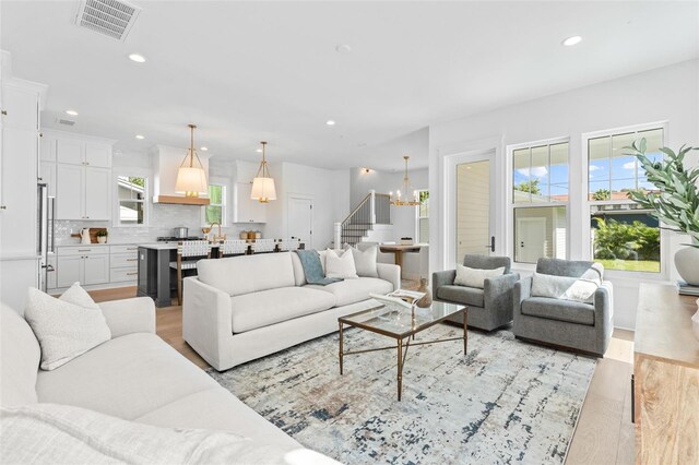 living area featuring stairway, light wood-type flooring, visible vents, and recessed lighting