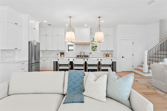 living area featuring stairs, light wood-type flooring, visible vents, and recessed lighting