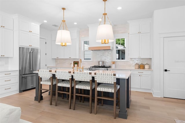 kitchen with white cabinets, light wood-type flooring, high end refrigerator, and light countertops