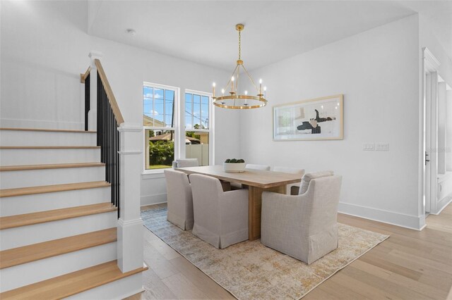 dining space featuring an inviting chandelier, baseboards, stairway, and wood finished floors