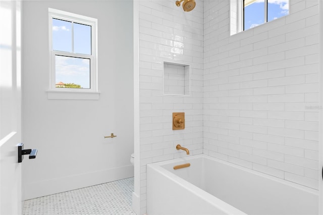 full bathroom with washtub / shower combination, tile patterned flooring, toilet, and baseboards