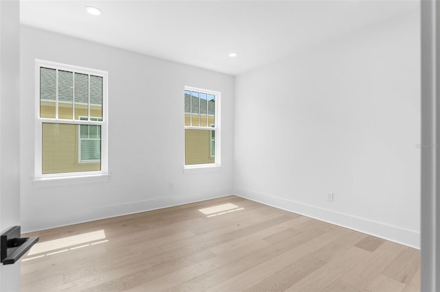 empty room with light wood finished floors, recessed lighting, and baseboards