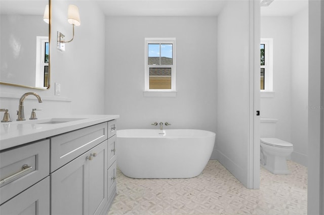 full bath featuring toilet, a soaking tub, vanity, and tile patterned floors