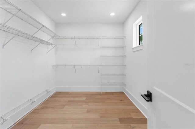 walk in closet with light wood finished floors