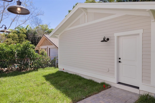 view of exterior entry featuring a yard and fence