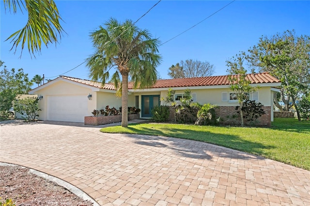 view of front of house featuring an attached garage, brick siding, decorative driveway, stucco siding, and a front lawn