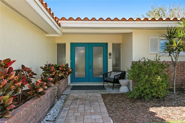 property entrance featuring french doors, a tiled roof, and stucco siding