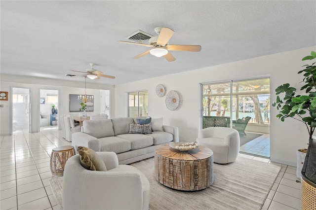 living area with visible vents, ceiling fan, a textured ceiling, and light tile patterned floors