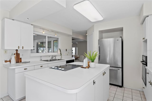 kitchen featuring light tile patterned floors, a sink, a kitchen island, white cabinetry, and black appliances