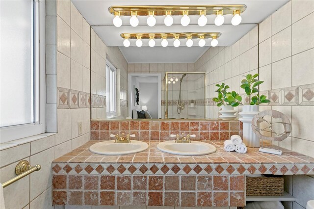 bathroom with a sink, a stall shower, and tile walls