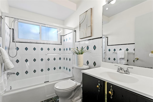 bathroom featuring toilet, enclosed tub / shower combo, tile walls, and vanity