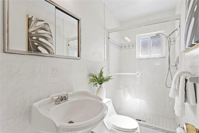 full bath featuring toilet, a stall shower, tile walls, and a sink