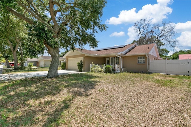 ranch-style house featuring a garage, a gate, solar panels, and stucco siding