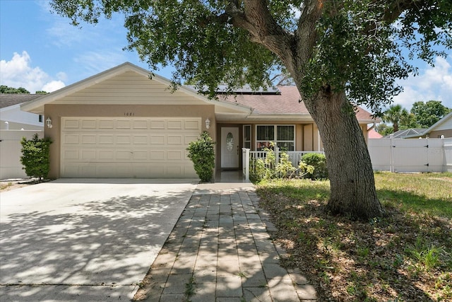 single story home featuring a garage, fence, concrete driveway, roof mounted solar panels, and stucco siding