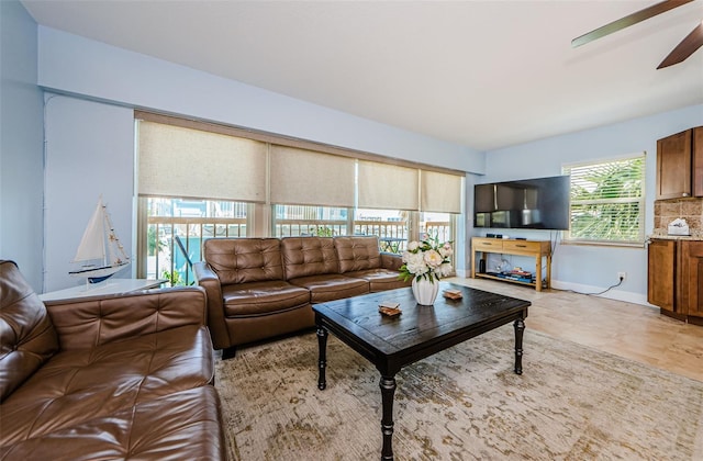 living area with baseboards and a ceiling fan