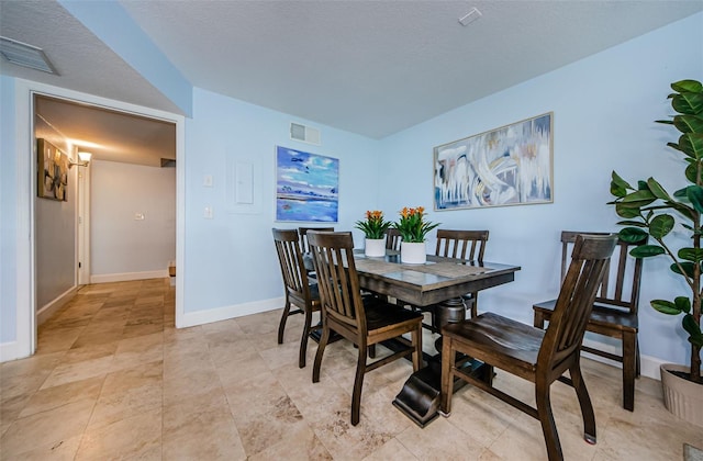 dining room featuring a textured ceiling, visible vents, and baseboards