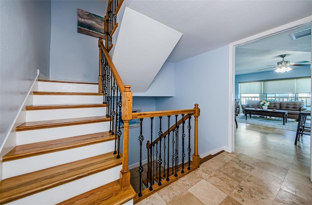 staircase featuring baseboards, visible vents, and ceiling fan