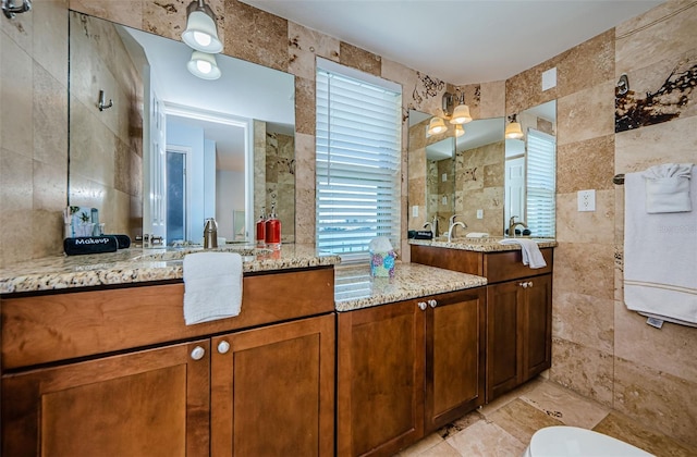 full bathroom with a tile shower, tile walls, and vanity