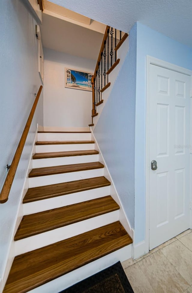 staircase with baseboards and tile patterned floors