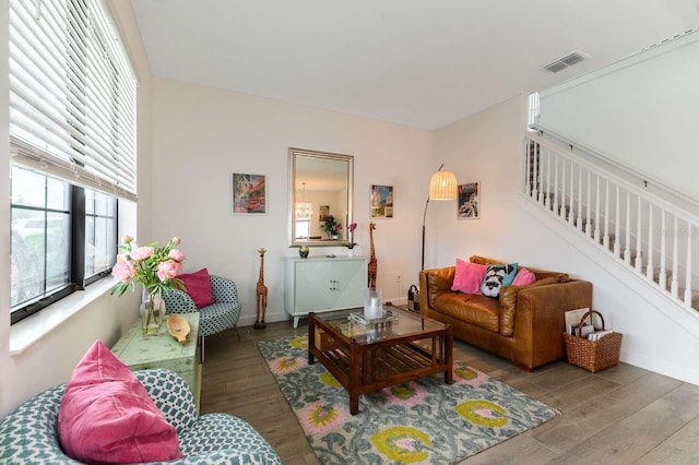 living area with stairway, baseboards, visible vents, and wood finished floors