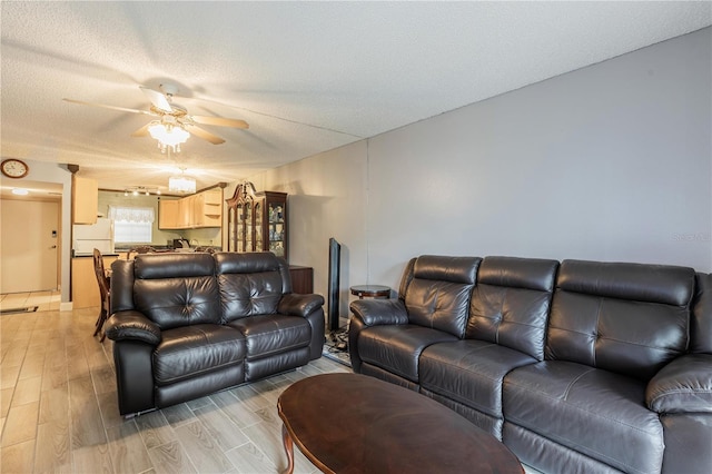 living room with a textured ceiling, light wood-type flooring, and a ceiling fan