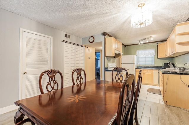 dining room with light wood-type flooring, visible vents, a chandelier, and a textured ceiling