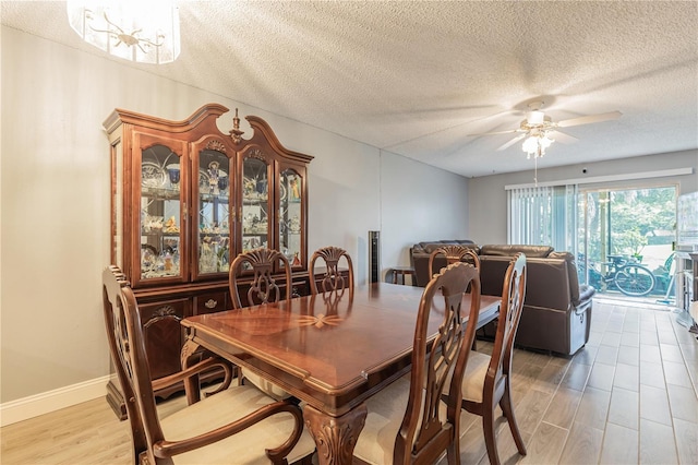 dining area with a textured ceiling, light wood-style floors, baseboards, and ceiling fan