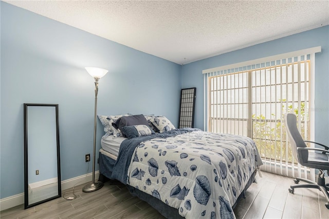 bedroom with a textured ceiling, baseboards, and wood tiled floor