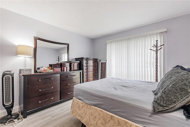 bedroom with a textured ceiling and light wood-style floors