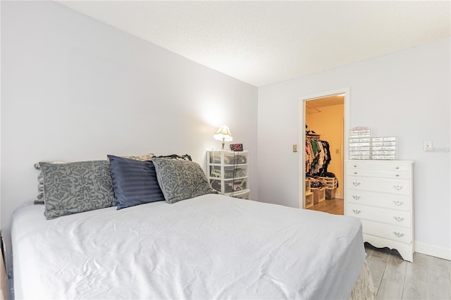 bedroom featuring a walk in closet and wood finished floors