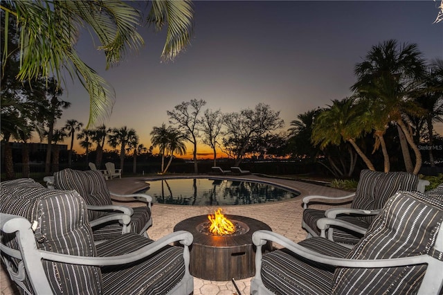 patio terrace at dusk with an outdoor pool and a fire pit